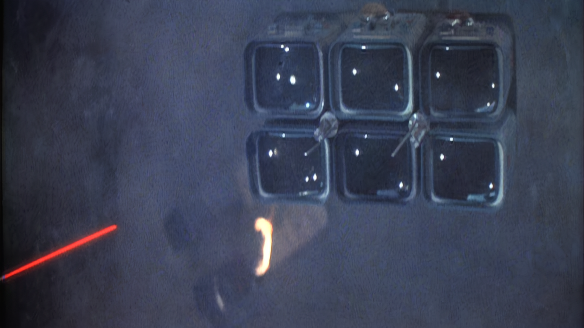Star Wars still of a red laserbeam about to hit a cluster of six square glass lights, possibly a security camera